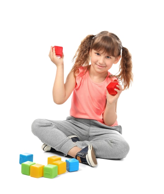 Linda chica divertida jugando con cubos sobre fondo blanco.