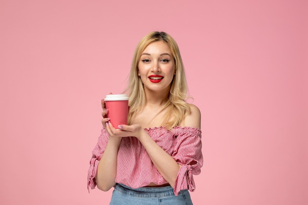 Linda chica encantadora jovencita con lápiz labial rojo en blusa rosa con vaso de papel rosa