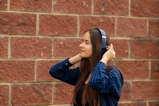 Linda chica escuchando música con auriculares en una calle de la ciudad