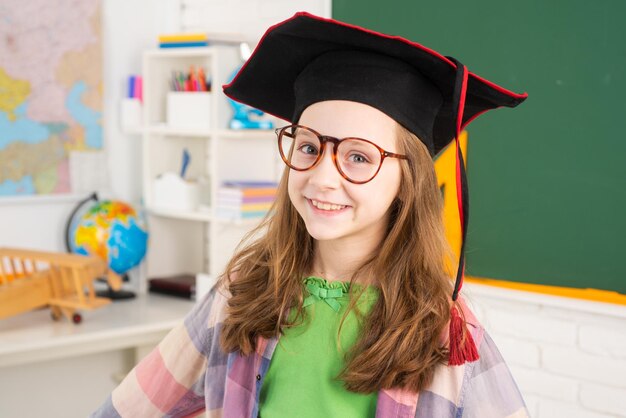 Linda chica en la escuela primaria en gorra universitaria