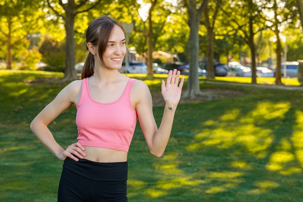 Linda chica en forma se para en el parque y le da la mano