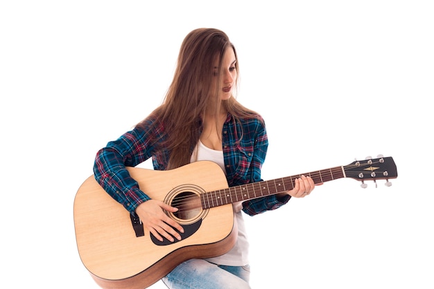 Linda chica con guitarra en manos sonriendo aislado sobre fondo blanco.