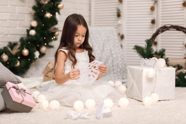 Linda chica haciendo copos de nieve de papel para decorar la Navidad