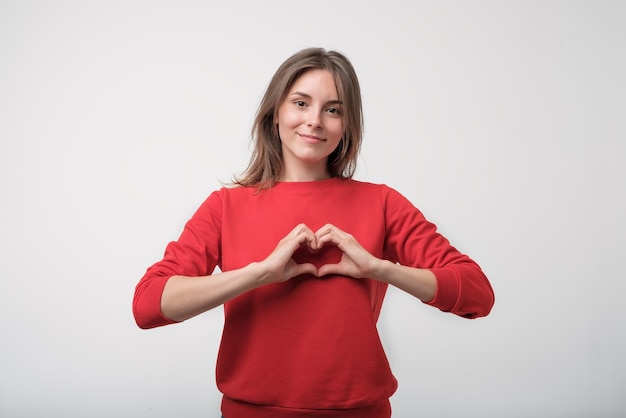 Linda chica hermosa enamorada haciendo corazón con los dedos y sonriendo