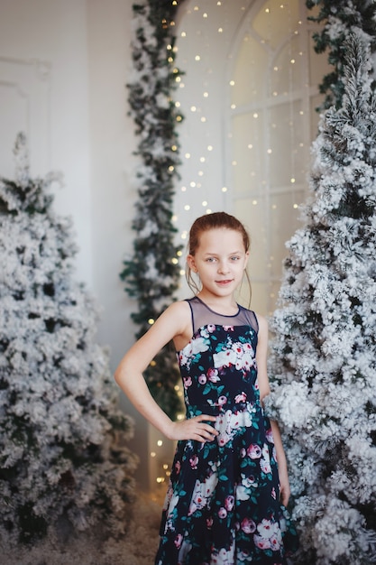 Linda chica en un hermoso vestido cerca de un árbol de Navidad