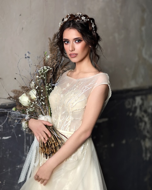 Linda chica con un hermoso vestido de novia. Retrato de la novia con un ramo de flores en sus manos.