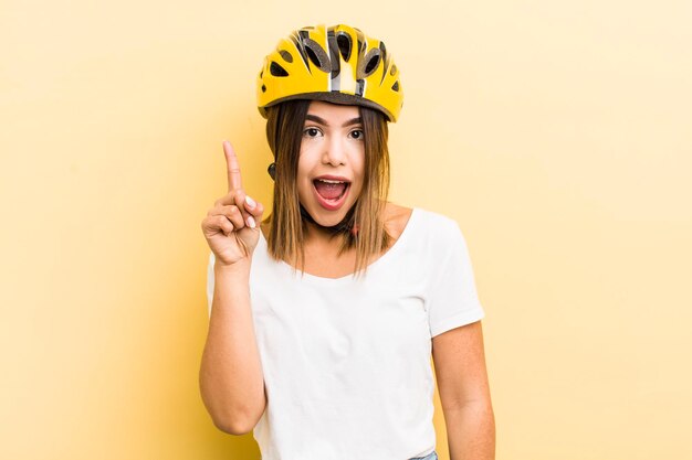 Linda chica hispana sintiéndose como un genio feliz y emocionado después de darse cuenta de un concepto de bicicleta de idea