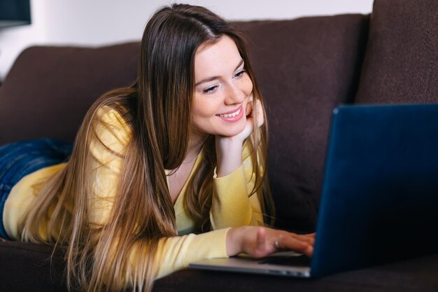 Linda chica independiente rubia sonriente trabajando en la computadora portátil