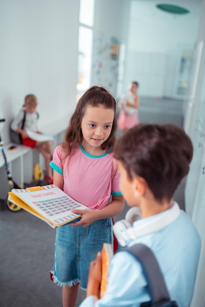 Linda chica inteligente ayudando a su nuevo compañero de clase con el horario