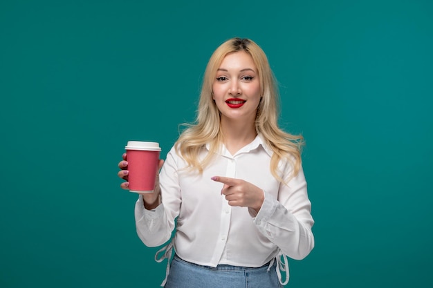 Linda chica joven adorable chica bonita en una camisa blanca limpia apuntando a una taza de café rosa