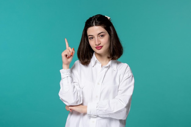 Linda chica joven bastante adorable chica morena con camisa blanca apuntando hacia arriba y pensando