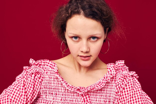 Linda chica joven en camisa rosa gesticulando con sus manos estudio fondo rojo