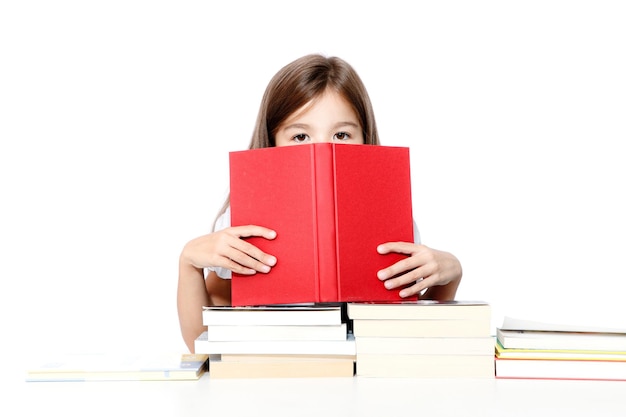 Linda chica joven sentada en la mesa y leyendo un libro