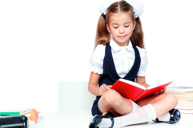 Linda chica joven sentada en la mesa y leyendo un libro