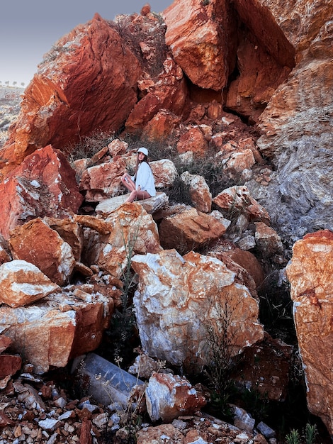 Linda chica joven se sienta en las rocas en el cañón de piedra