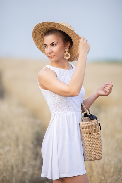 Linda chica joven en un sombrero de paja en un campo de trigo