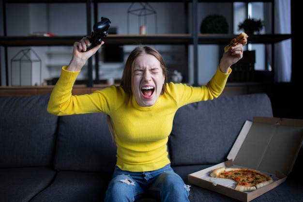 Linda chica juega en la consola y come pizza