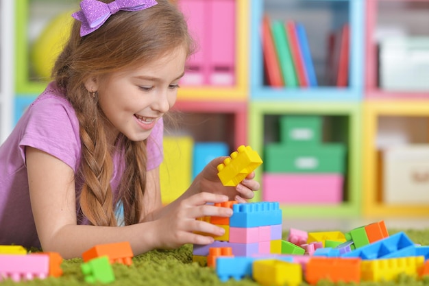 Linda chica jugando con coloridos bloques de plástico en la habitación