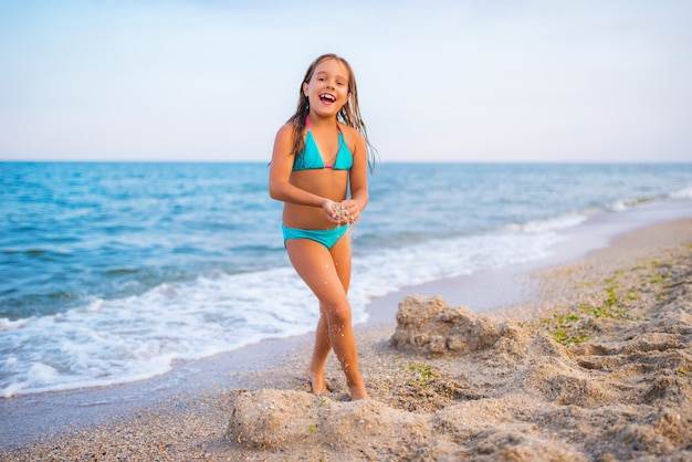 Linda chica jugando en la playa junto al mar