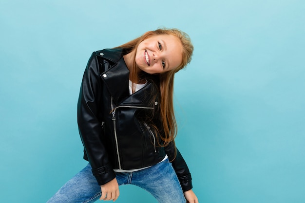 Linda chica en un look casual con una chaqueta de cuero y jeans inclinó su cabeza hacia un lado