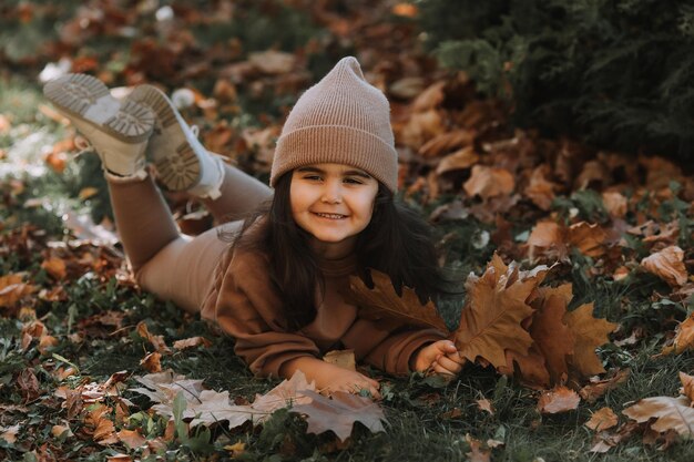 Una linda chica morena acostada en la hierba en otoño