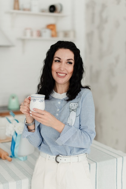 Linda chica morena con una camisa azul bebe de una taza