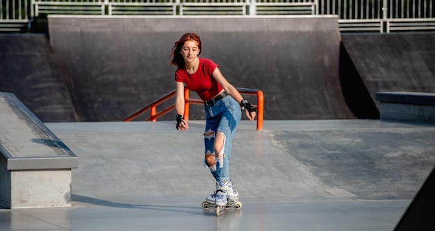 Linda chica en patines montando en la ciudad en la rampa del parque. Adolescente femenino patinar al aire libre