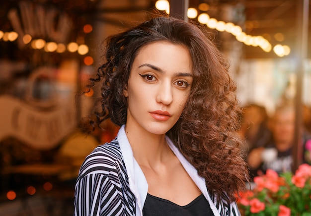 Linda chica con el pelo ondulado, retrato de una niña en un café.