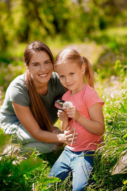 Linda chica con una pelota en las manos pasando tiempo con su madre en el bosque