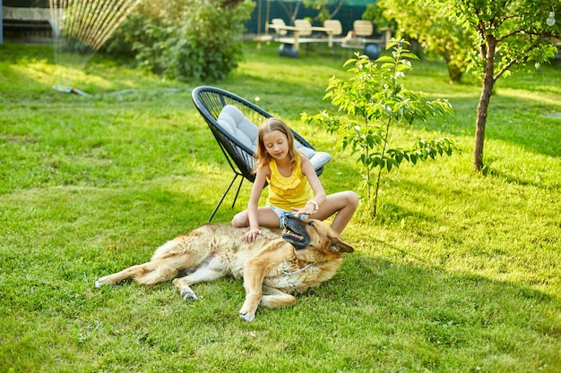 Linda chica y perro viejo disfrutan del día de verano en el césped del parque