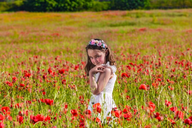 Linda chica de pie en el campo de flores florecientes