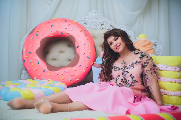 Linda chica posando con rosquillas rosas, jugando, postre, mala comida, mira el agujero en la rosquilla, mantiene las rosquillas a los ojos