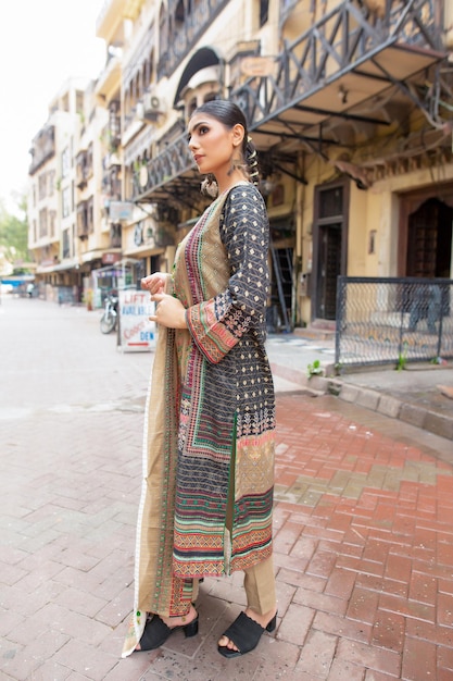 Linda chica pose lateral mostrando su ropa Desi para sesión de fotos de moda en la calle de la ciudad amurallada de Lahore