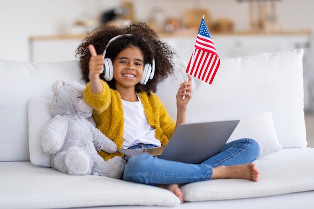 Linda chica preadolescente afroamericana teniendo clase de inglés en Internet