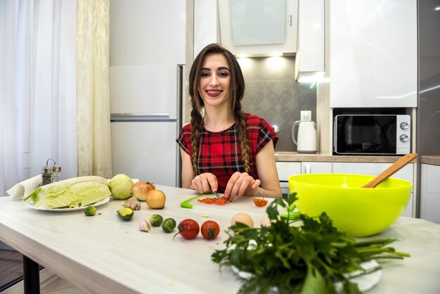 Linda chica prepara una ensalada de diferentes verduras y verduras para un estilo de vida saludable