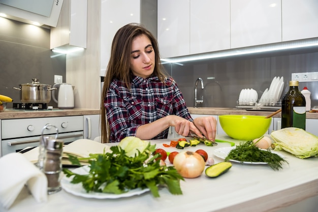 Linda chica prepara una ensalada de diferentes verduras y verduras para un estilo de vida saludable