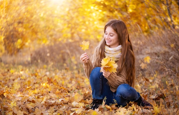 Linda chica recogiendo hojas de otoño