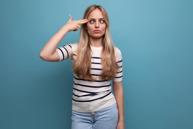 Linda chica con ropa informal muestra un dedo en el gesto de la cabeza en un fondo azul aislado