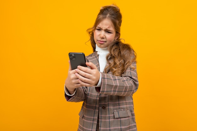 Linda chica rubia caucásica en una chaqueta clásica hace selfie en el teléfono con un amarillo