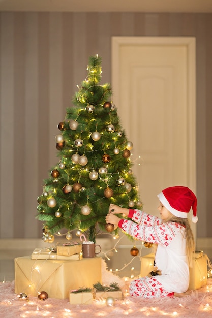 Linda chica rubia decorando el árbol de Navidad