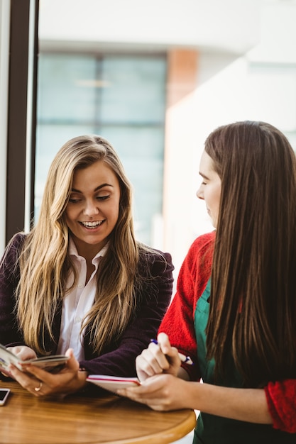 Linda chica rubia ordenando a su amiga en una cafetería