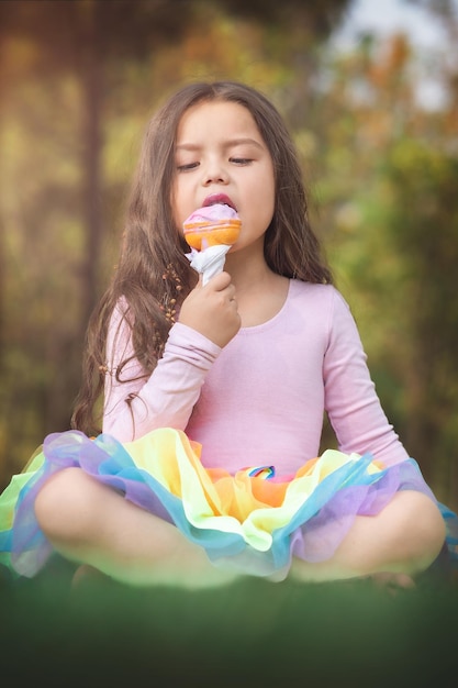 Linda chica rubia de pelo rizado comiendo un buen helado en el concepto del parque del día de los niños