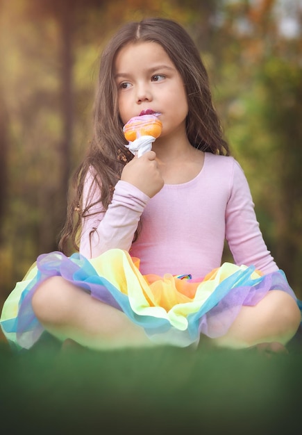 Linda chica rubia de pelo rizado comiendo un buen helado en el concepto del parque del día de los niños