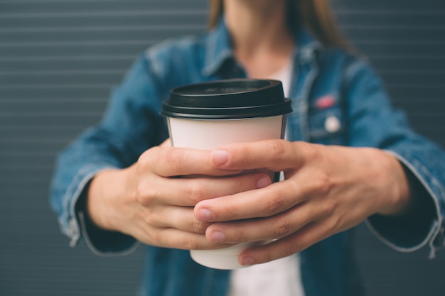 Linda chica sentada en la calle con café de la mañana y relajante