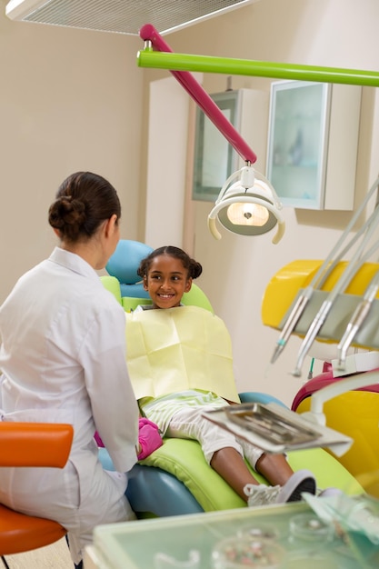 Linda chica sentada frente a un dentista