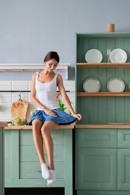 Linda chica sentada en la mesa de su cocina y esperando el desayuno