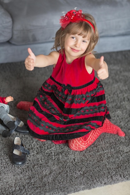 Linda chica sentada en el suelo y jugando con su muñeca. Concepto de infancia feliz