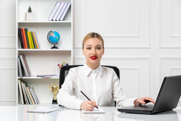 Linda chica de servicio al cliente con camisa blanca con lápiz labial rojo y computadora portátil tomando notas