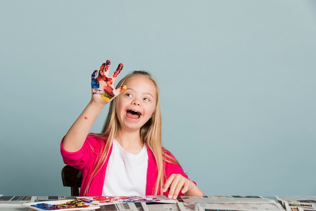 Foto linda chica con síndrome de down jugando con pinturas