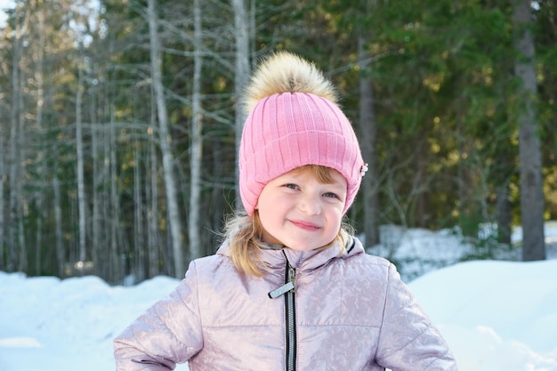 Linda chica en un soleado día de invierno con el telón de fondo de la nieve y el bosque